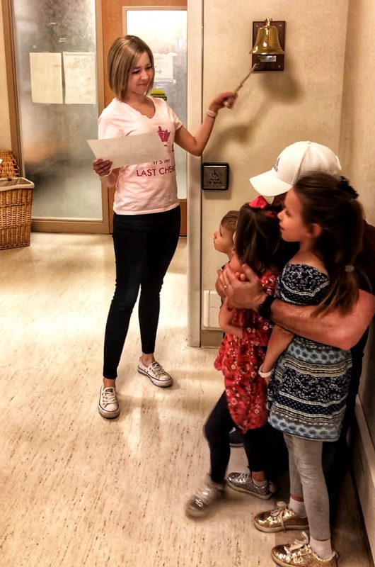Marisa ringing the bell with her daughters
