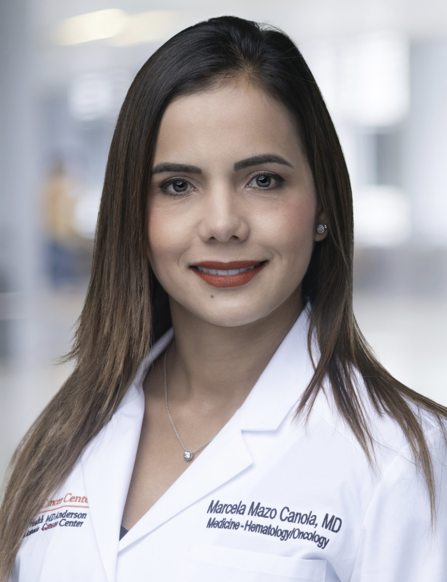 Dr. Marcela Mazo in white lab coat with long brown hair and red lipstick